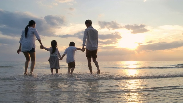 快乐的亚洲家庭在日落的海滩上跑步，旅游的概念。缓慢的运动。视频下载