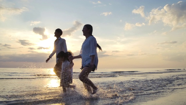 快乐的亚洲家庭在日落的海滩上跑步，旅游的概念。缓慢的运动。视频素材