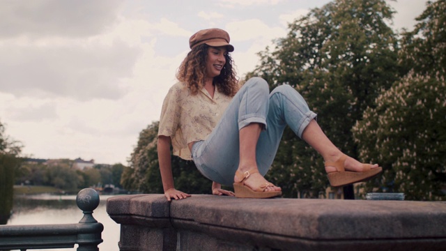 一名年轻女子爬上柏林施普雷河边的一堵墙，坐下来吃蓝莓视频素材