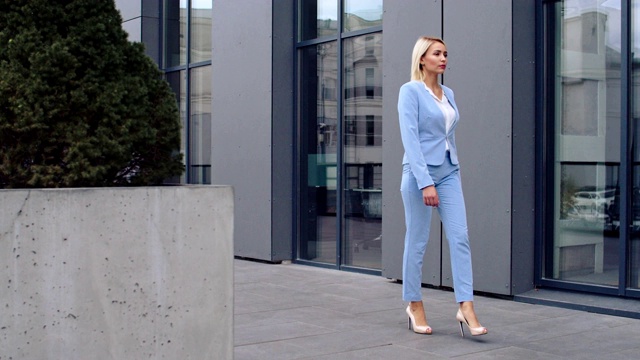 从侧面看，这位时尚迷人的白人女性，行政办公室工作人员走在城市大楼的街道上，正要去上班或参加正式会议。视频下载