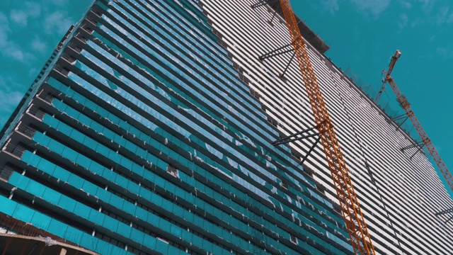 蓝天下建筑工地上的起重机正在建造新的摩天大楼。建筑施工视频素材