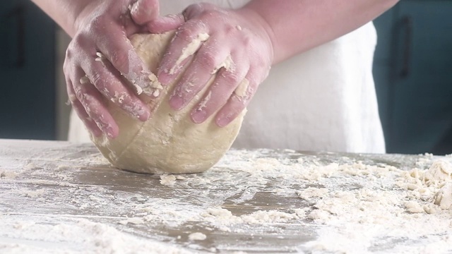 面包师揉面团做馅饼。用脏手在桌上揉面团。慢镜头特写。视频素材