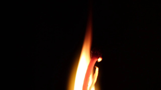 一根燃烧着的火柴在黑暗的背景上视频素材