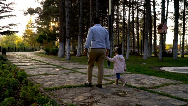 年轻的父亲和女儿在城市公园散步视频下载