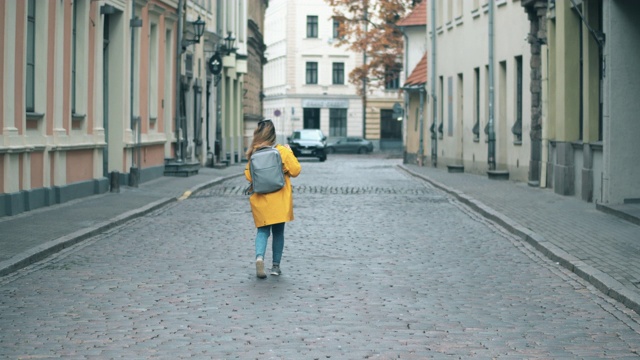 一位妇女走在城市历史街区的街道上。视频素材