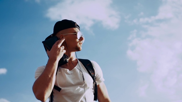 年轻人戴着耳机在天空背景上跳舞视频素材