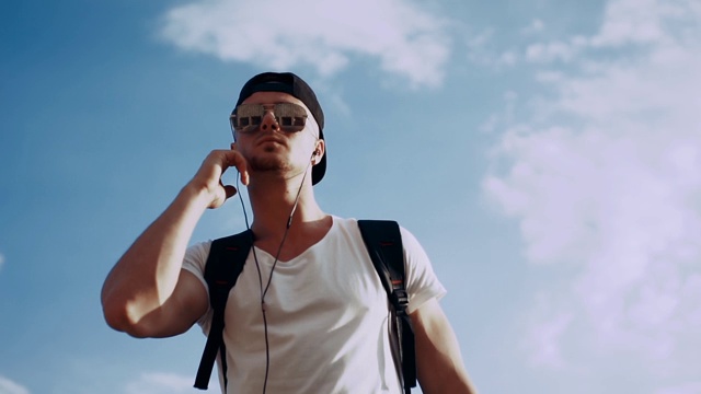 年轻人戴着耳机在天空背景下跳舞视频素材