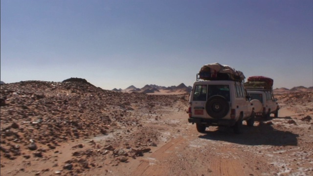 一辆休旅车开在Gilf Kebir崎岖的土路上。视频下载