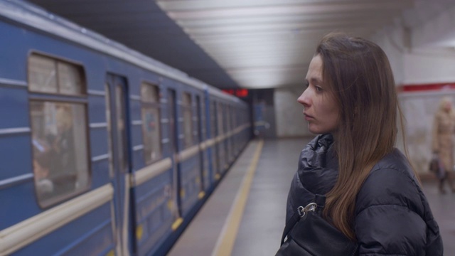 一个女人站在离发车不远的地铁站台上的侧面肖像视频素材