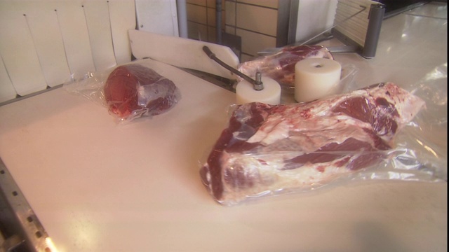 塑料包装的牛肉在传送带上运输。视频下载