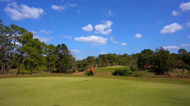 慢镜头高尔夫旗子在风大的高尔夫球场，美丽的球道，蓝天绿草的布局视频素材