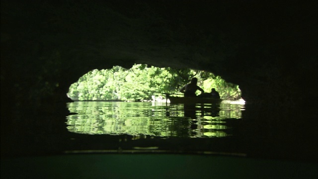一个女人领着独木舟走出一个狭窄的洞穴。视频下载