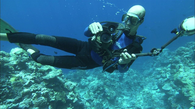 在帕劳礁的海床上，一名潜水员正在调整他的水下摄像机。视频下载