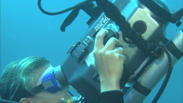 一名潜水员在水下操作摄像机。视频下载