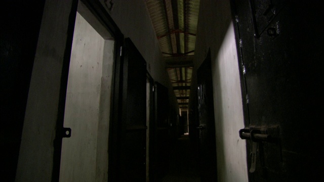 一条狭窄的走廊通向一间空荡荡的越南监狱的牢房门。视频素材