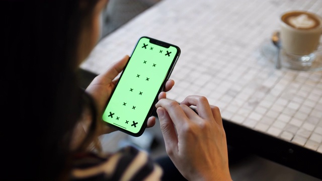 一名年轻女子在咖啡馆使用绿色屏幕的智能手机视频素材