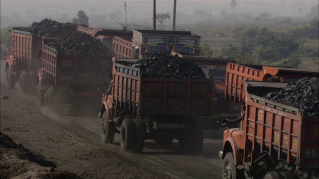 运煤的卡车在一个建筑工地的土路上行驶。视频素材