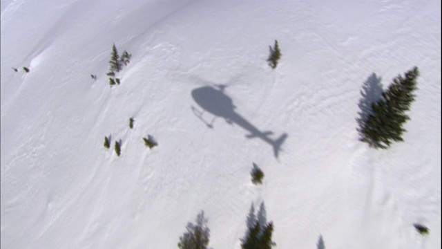 一架直升机在雪景上投下了阴影。视频下载