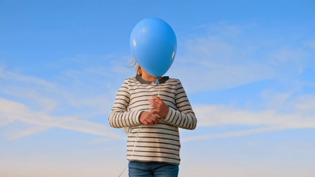 SLO MO女孩放飞一个蓝色的气球，仰望天空视频素材