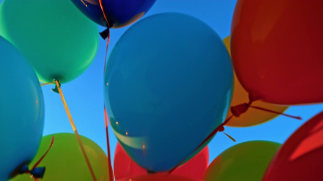 SLO MO LD彩色气球绑在一起漂浮在蓝色的天空视频素材