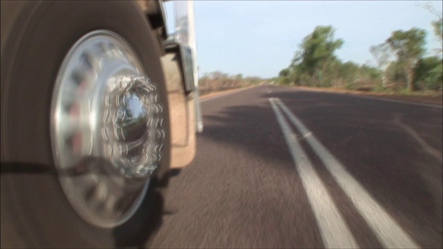 在澳大利亚内陆，一辆公路列车的右前轮沿着一条乡村公路的中心线行驶。视频下载