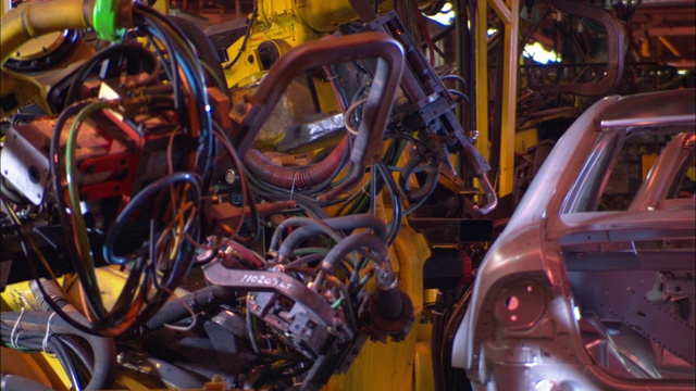 随着火花飞溅，汽车机器人在装配线上焊接一辆汽车。视频素材