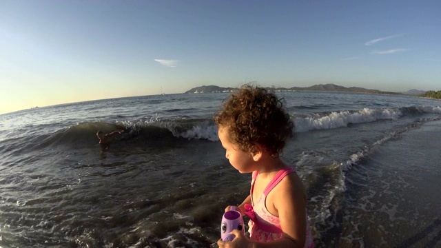 小女孩/孩子在沙滩上玩喷壶/玩具-大海，大海，夏天的时候视频下载