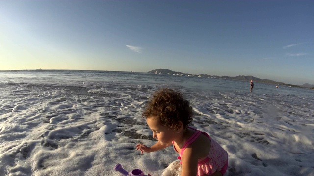 小女孩/孩子在沙滩上玩喷壶/玩具-大海，大海，夏天的时候视频下载