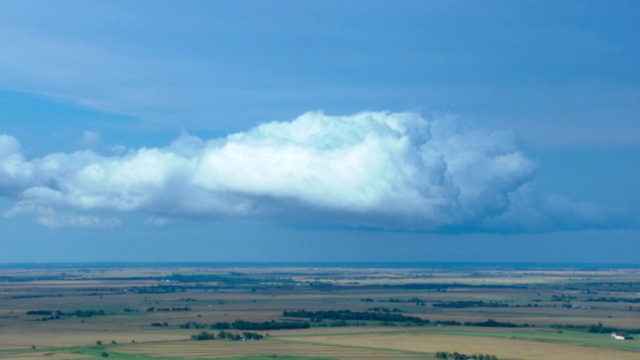 一大片云漂浮在农田上空。视频下载
