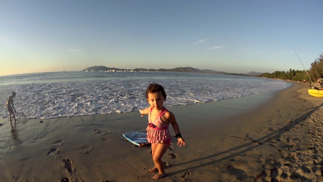 小女孩/孩子在沙滩上玩滑板/玩具-大海，海洋，夏天的时间，日落视频下载