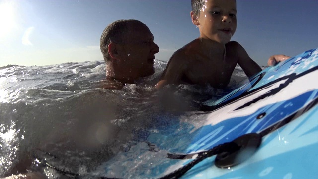 父子-男孩/孩子冲浪-跳跃的海浪身体板/在海滩冲浪，冲浪，冲浪视频下载