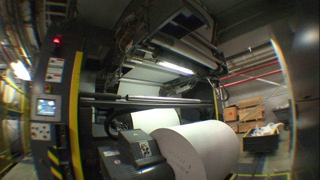 一个工人检查印刷机。视频下载
