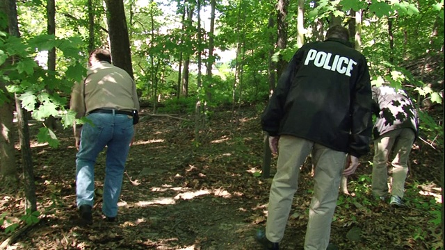 两名警探搜查森林地面。视频下载