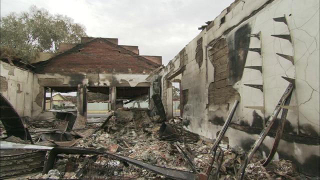 烧焦的瓦砾覆盖着一所被摧毁的房子的地板。视频素材