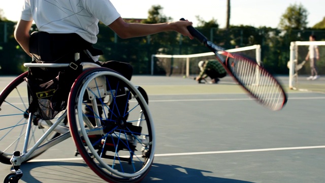 一个坐在轮椅上打网球的少年的中景视频素材
