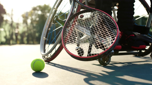 SLO MO CU:一个适应性运动员用他的球拍从地上捡起一个网球视频下载
