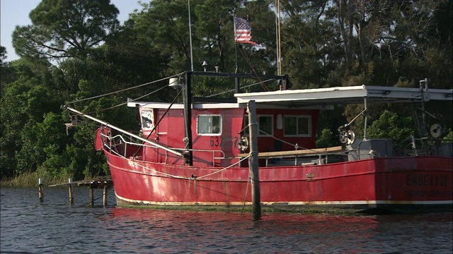 一艘质朴的红船停靠在河岸上。视频下载