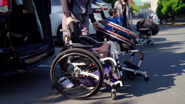 一个成年人把轮椅从车后面拖出来的广角镜头视频素材