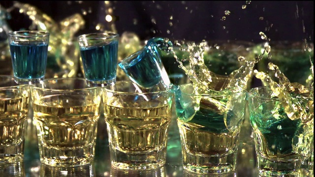在慢镜头中，小酒杯落入酒杯。视频下载