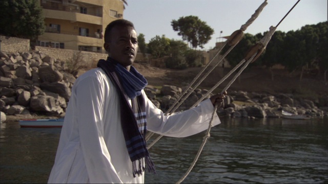 一名埃及船夫在尼罗河上航行时拿着船单。视频下载