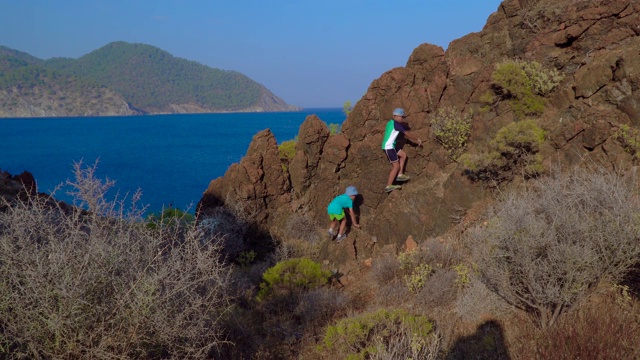 男孩们爬上了地中海岸边的岩石视频下载