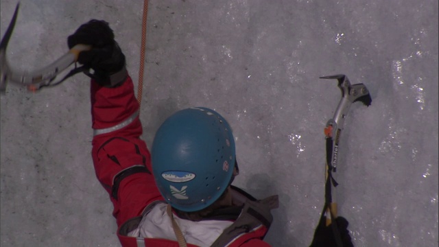 冰攀者使用冰斧和冰爪爬上冰墙。视频素材