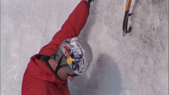 一个冰上攀岩者用鹤嘴锄凿墙。视频素材
