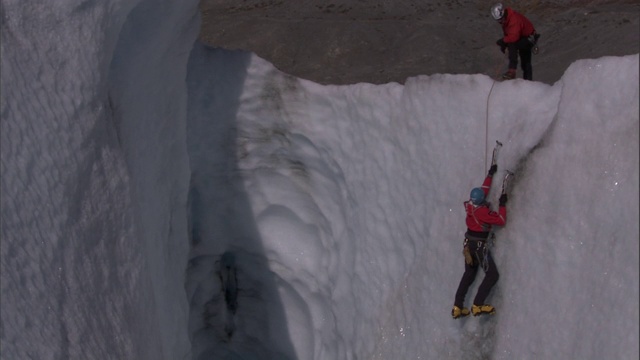 在阿拉斯加，一队登山者攀登被冰雪覆盖的悬崖。视频素材
