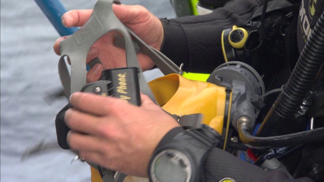 一名潜水员正在修理他面罩的橡胶带。视频下载