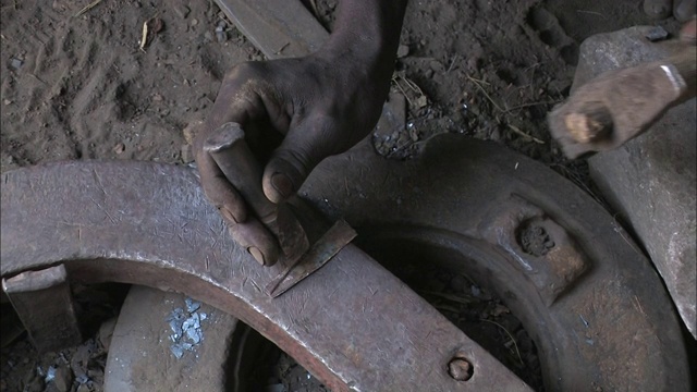 铁匠用锤子在一块金属上凿出凹槽。视频素材