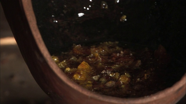 一个男人的手把一团土豆泥浸入一个蜂蜜碗里。视频下载