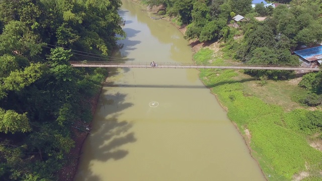 骑着摩托车飞过一条小河上的吊桥视频素材