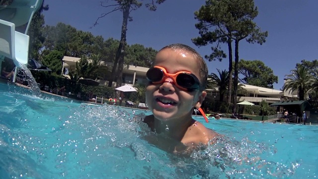 男孩在游泳池滑梯上滑-在游泳池里跳和跳水视频下载