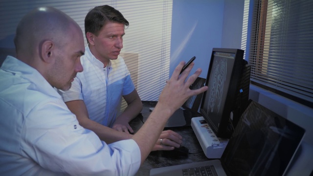 在控制室，医生和放射科医生一边看程序一边讨论诊断。MRI或CT扫描程序。视频素材
